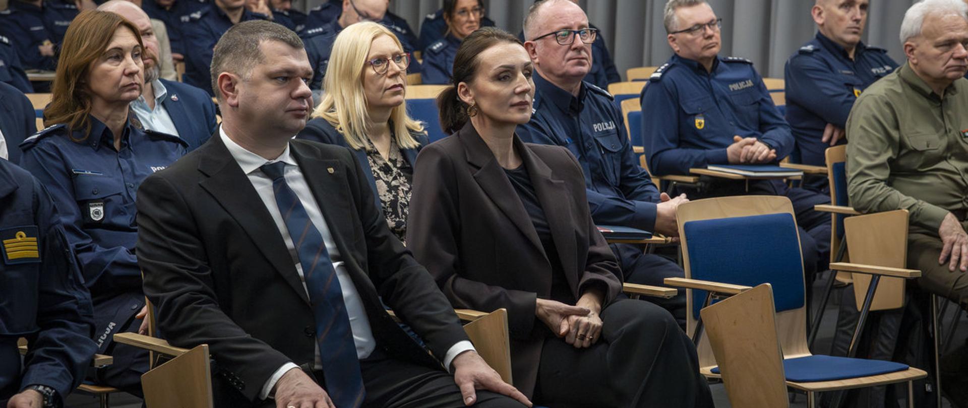grupa osób w tym w mundurach policyjnych siedzi w sali i ogląda prezentację