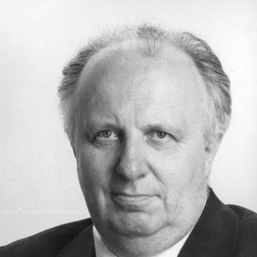 Stefan Olszowski - czarno - biały portret mężczyzny, siwiejące włosy, ciemna marynarka, ciemny krawat, biała koszula.