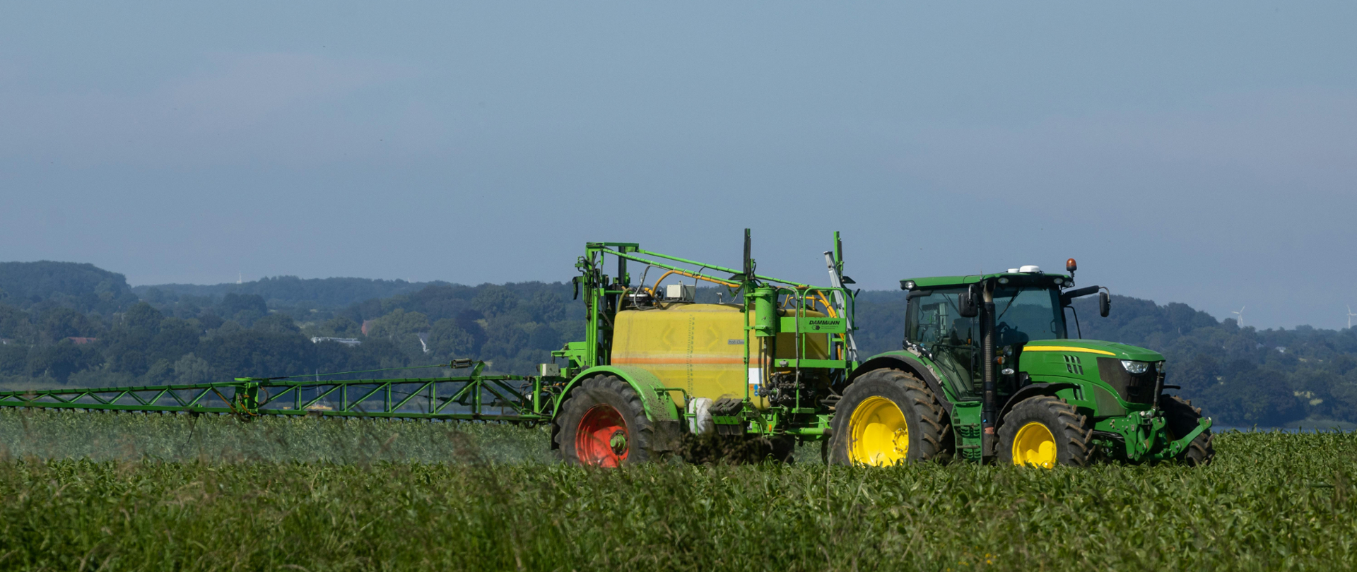Na zdjęciu widzimy traktor z doczepioną maszyną do robienia oprysków na polu uprawnym