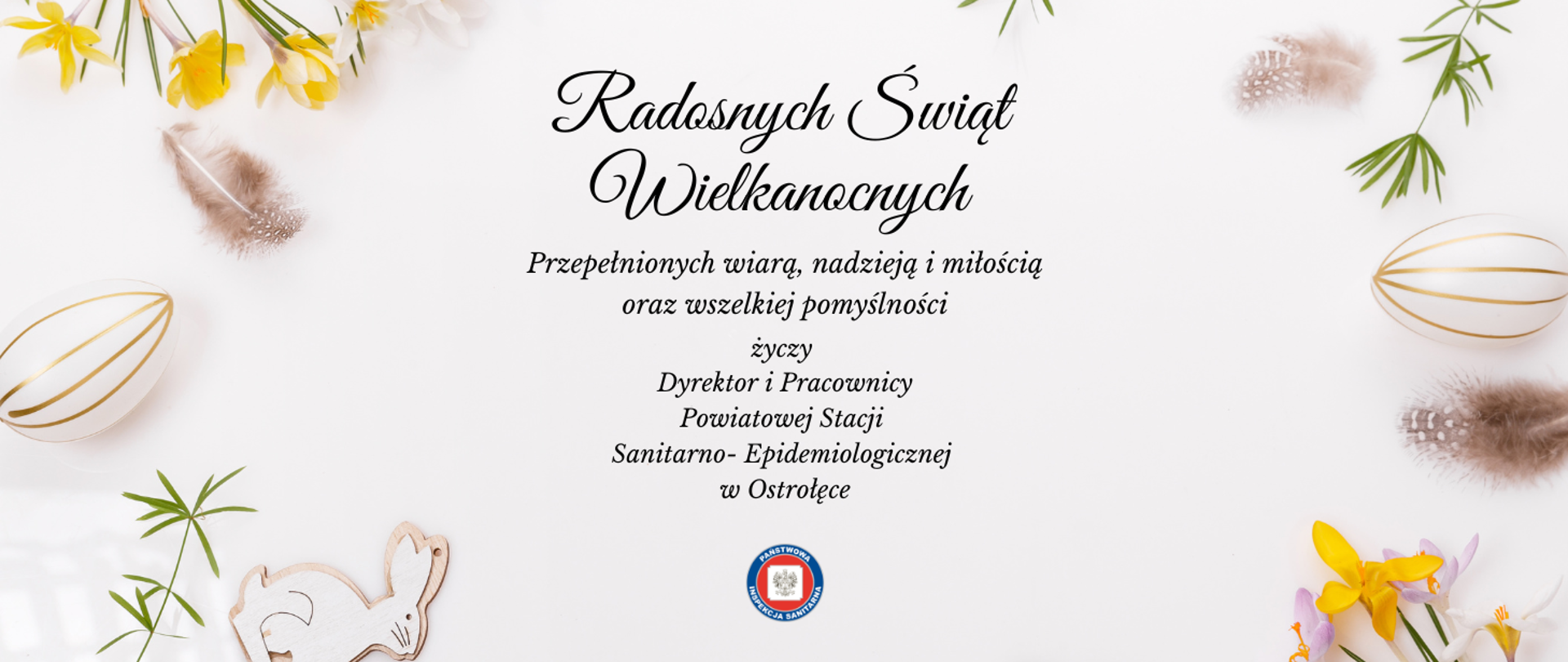 Na białym tle życzenia wielkanocne. Z prawej i lewej strony białe jajka w złote paski oraz brązowe piórka. W prawym dolnym i lewym górnym rogu żółte, białe i fioletowe kwiaty. W lewym dolnym rogu drewniana zawieszka zająca wielkanocnego.