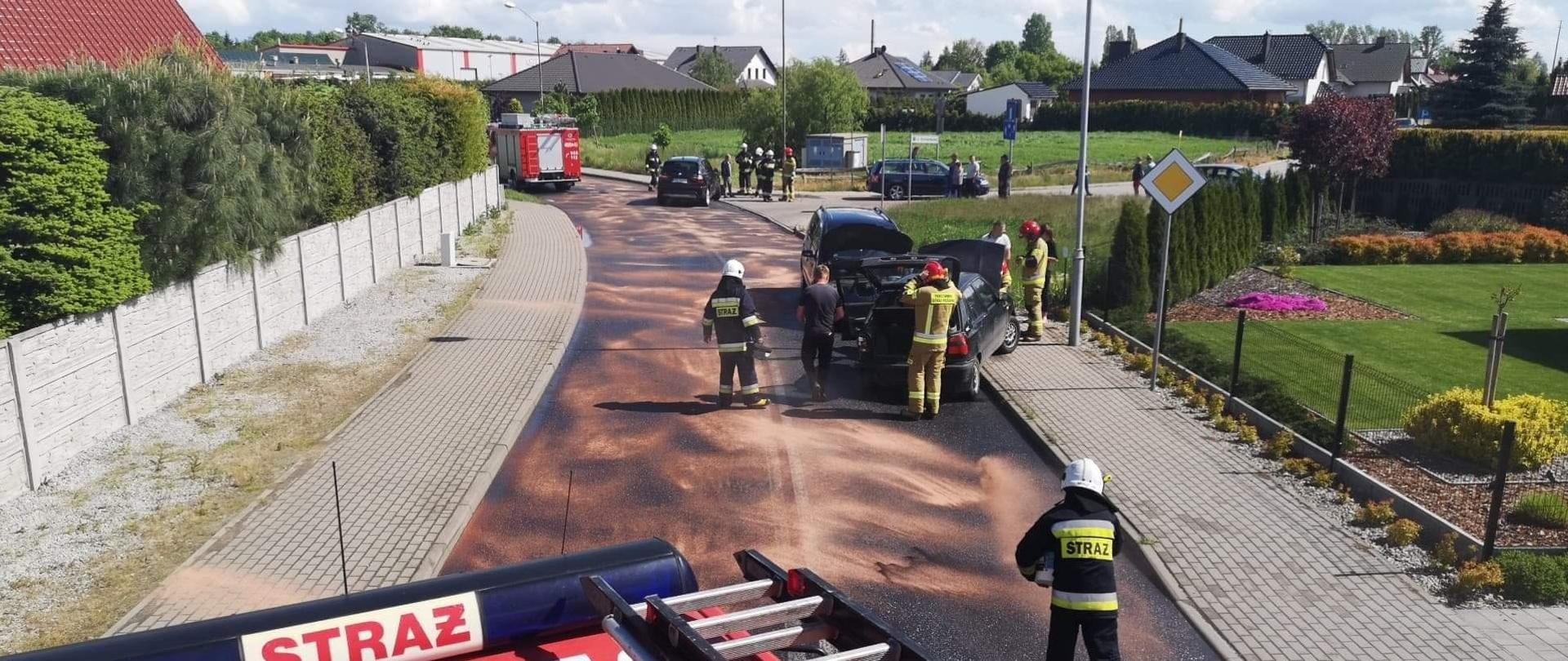 Kolizja drogowa czterech pojazdów oraz plama oleju na odcinku około 500 metrów. Cała szerokość jezdni posypana sorbentem. Droga całkowicie zablokowana przez pojazdy pożarnicze. Strażacy prowadzą działania zmierzające do usunięcia skutków kolizji oraz likwidacji zagrożenia z jezdni. Uszkodzone środki transportu blokują jeden pas jezdni. Osoby uczestniczące w zdarzeniu znajdują się w pobliżu pojazdów. 