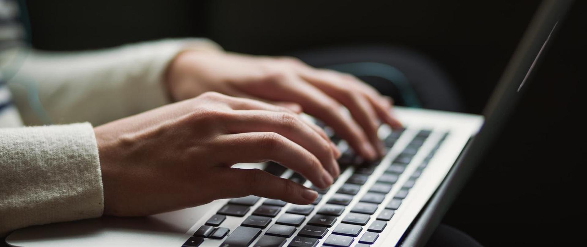 Ręce dotykają klawiatury laptopa