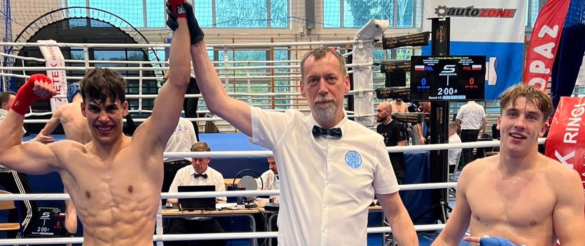 Sędzia podnosi rękę zwycięzcy, obok stoi pokonany zawodnik