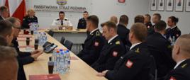 W sali sztabowej Komendy Wojewódzkiej PSP w Katowicach przy stole siedzą strażacy sportowcy, u szczytu stołu siedzi Śląski Komendant Wojewódzki PSP nadbryg. Jacek Kleszczewski z dwoma funkcjonariuszami 