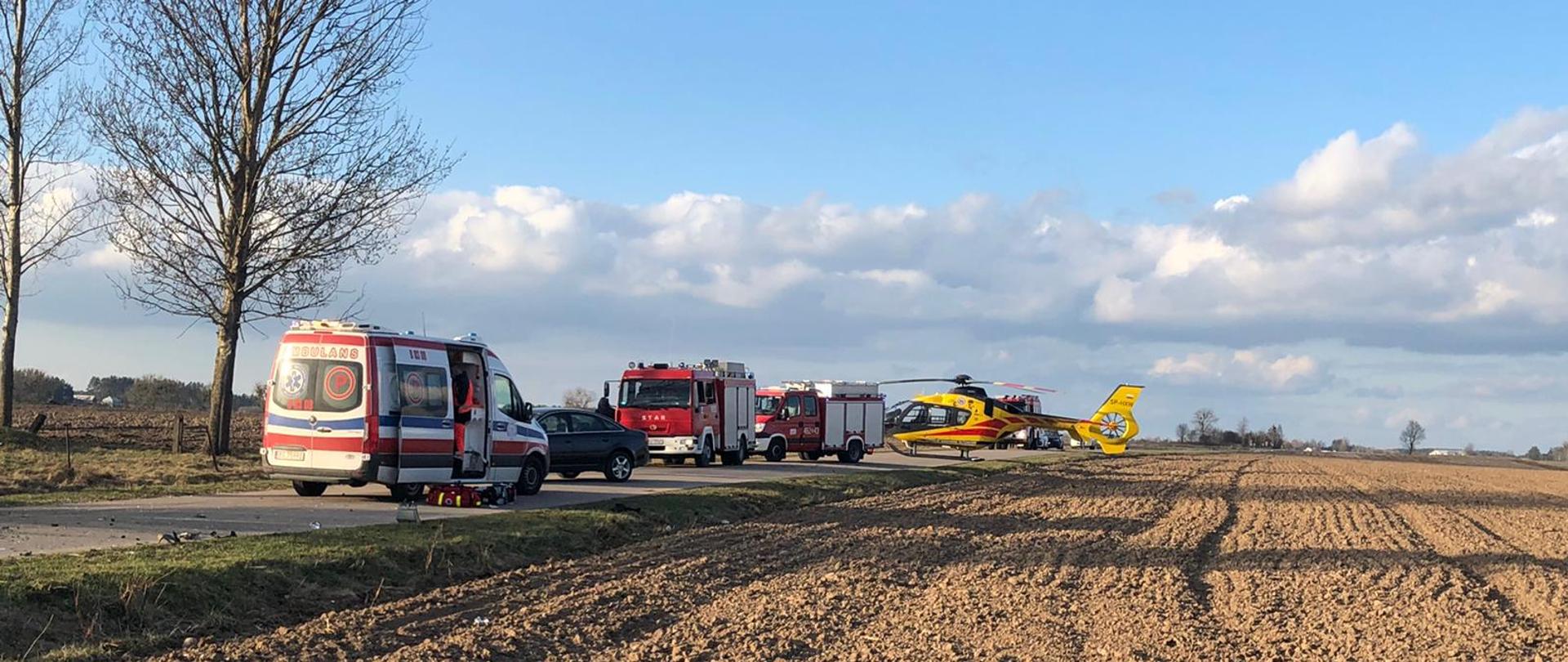 Na zdjęciu widać 2 samochody pożarnicze, ambulans oraz helikopter LPR