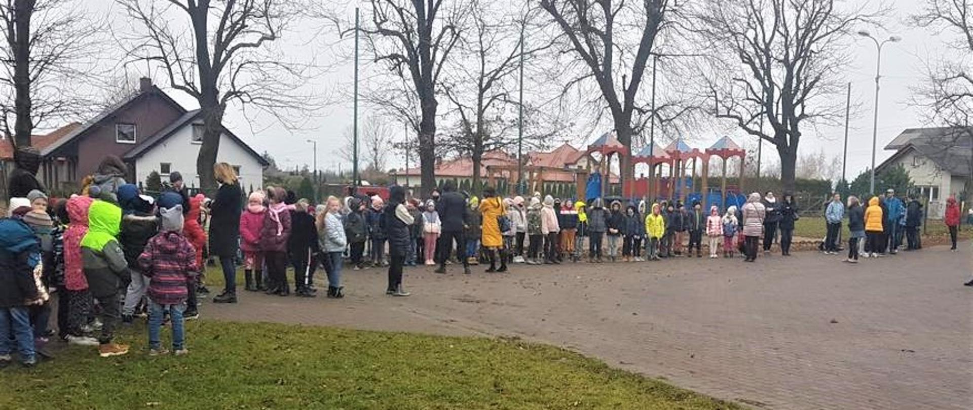 Dzieci stające w wyznaczonym miejscu zbiórki przed szkołą