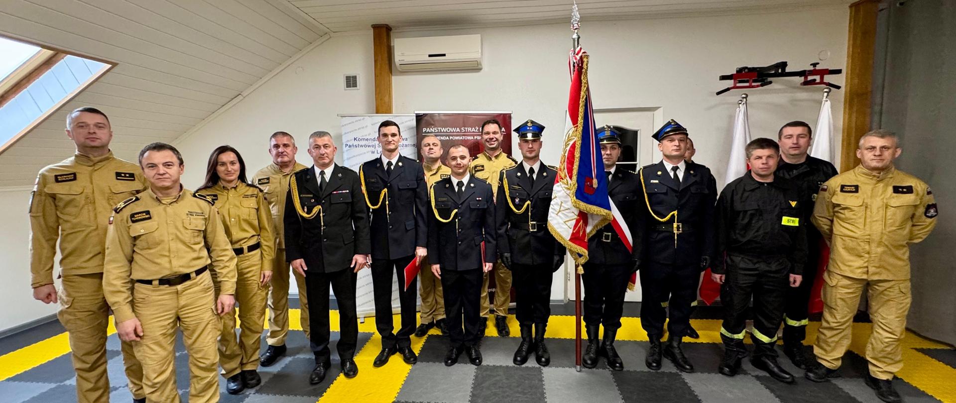 Zdjęcie przedstawia funkcjonariuszy i pracowników cywilnych KP PSP w Lesku podczas uroczystego apelu z okazji mianowania na wyższe stanowiska służbowe.