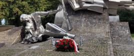 Wiązanka oraz dwa znicze leżą przed pomnikiem - mogiłą Obrońców Poczty Polskiej w Gdańsku.