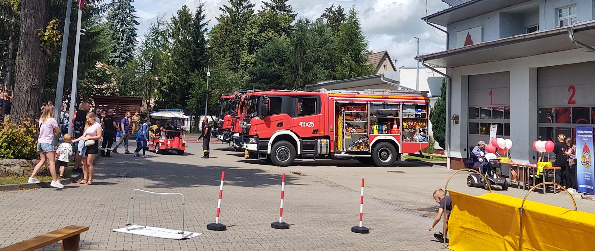 Na pierwszym planie tor przeszkód, w tle samochody pożarnicze, Melex, stoisko z gadżetami