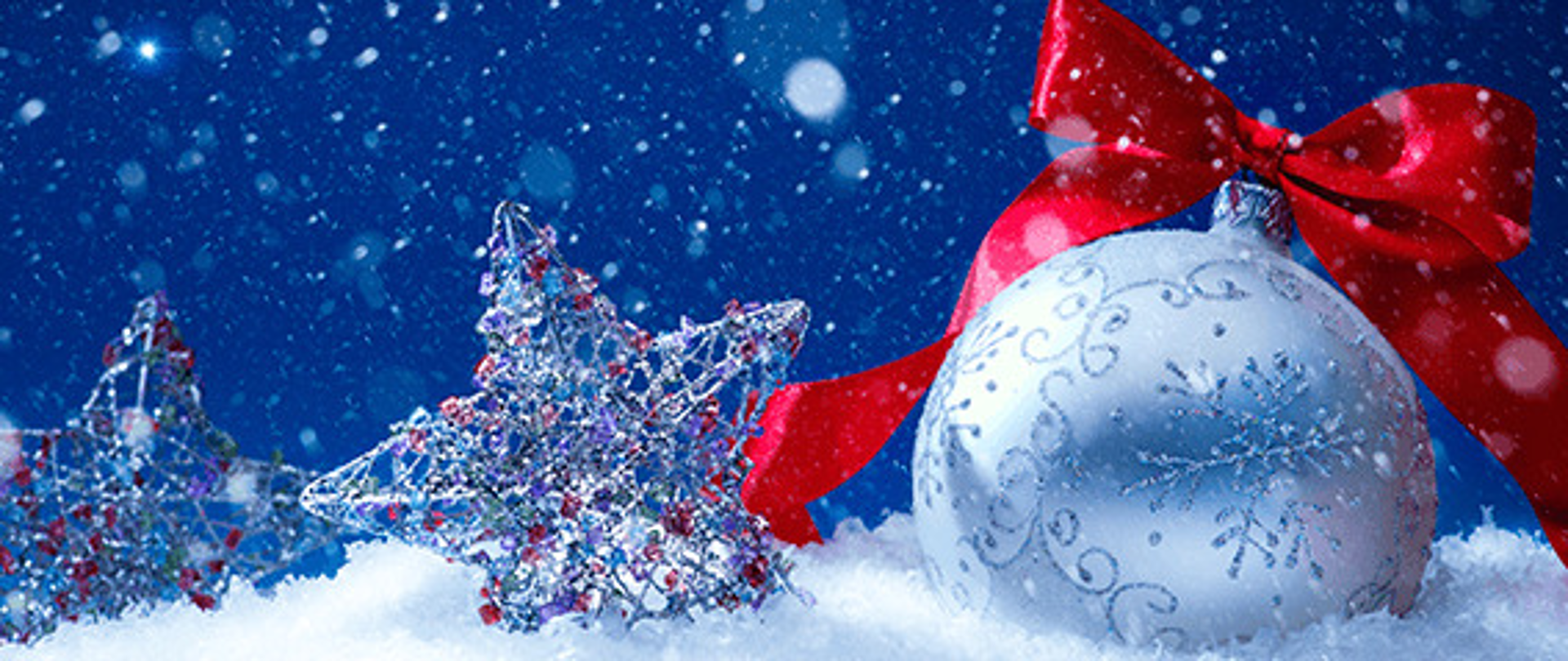 Życzenia świąteczne od dyrekcji i nauczycieli szkoły, na górze bombka i gwiazdki w śniegu, niebieskie niebo i padający śnieg
