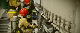Zdjęcie przedstawia strażaków przy naczepie samochodu ciężarowego którzy za pomocą kamery termowizyjnej sprawdzają temperaturę uszkodzonej opony, potwierdzając tym samym jej całkowite ugaszenie.