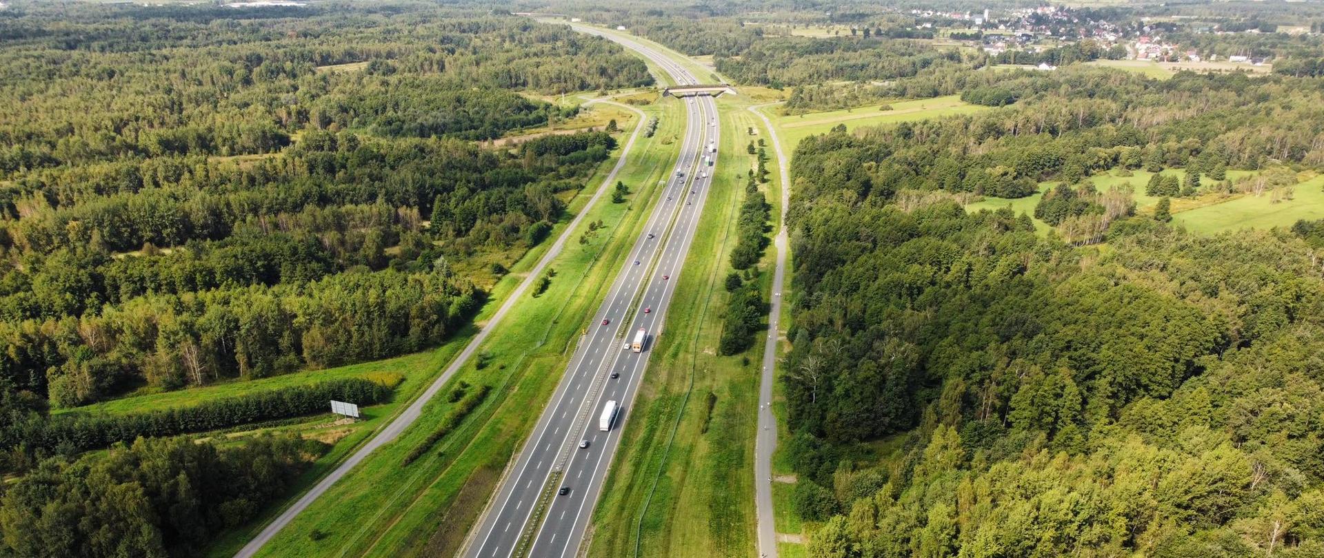 autostrada A4 Kraków Tarnów, zdjęcie zrobione z lotu ptaka, A4 biegnie wśród terenów leśnych, w oddali po prawej zabudowania
