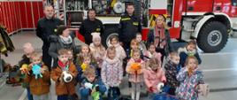 Na zdjęciu widać wycieczkę dzieci z pluszakami w JRG Kolno, w tle samochód pożarniczy.