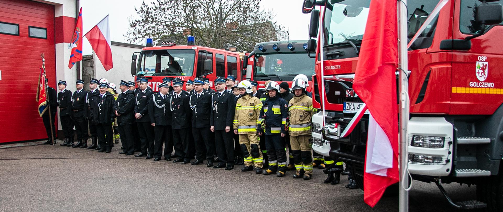 Na zdjęciu widoczni strażacy Ochotnicy wraz ze swoim sztandarem z OSP Golczewo. Za nimi stoją samochody ratowniczo gaśnicze, a tle widac ich remize.