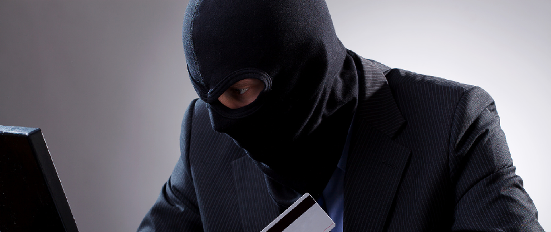 Zamaskowany mężczyzna przed laptopem