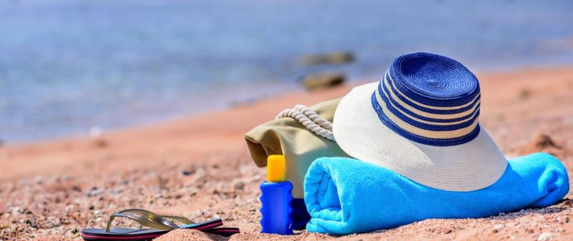 Ręcznik, kapelusz i krem do opalania na plaży w słoneczny dzień