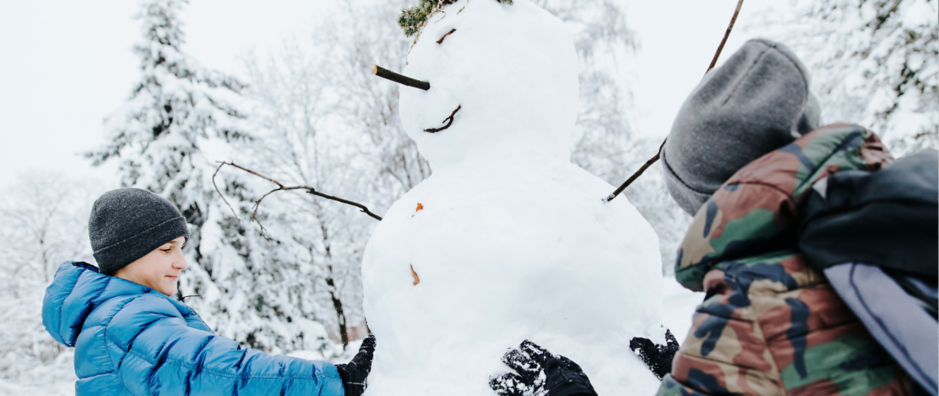 Dzieci lepią bałwana na śniegu podczas zimowego wypoczynku na świeżym powietrzu.
