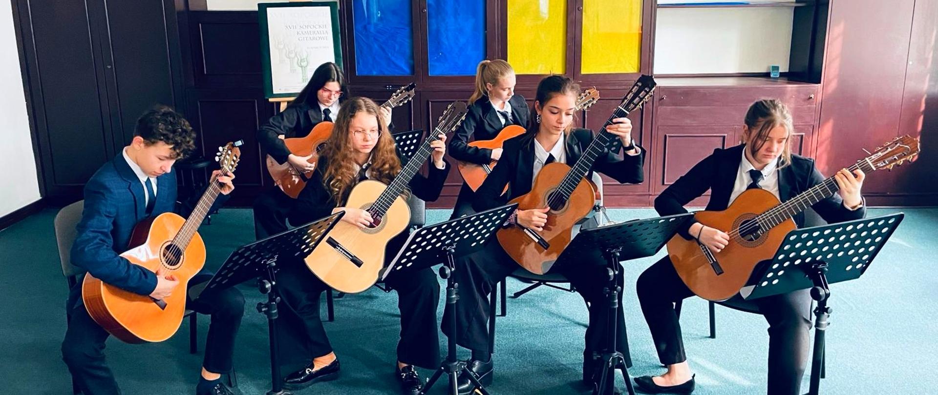 uczniowie grający na gitarach