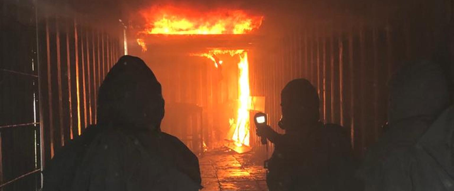 na zdjęci strażacy podczas ćwiczenia w kontenerze ogniowym widoczne płomienie ognia