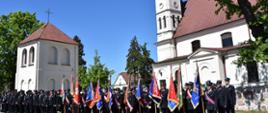 Pododdział strażaków i pocztów sztandarowych na tle kościoła przed uroczystym apelem 