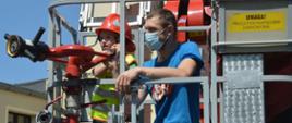 Wspieramy leczenie Gosi. Laureat licytacji "Dnia ze strażakami w Komendzie Powiatowej PSP w Rawiczu" z 3-letnim synem, w koszu podnośnika hydraulicznego. Chłopiec mający na sobie czerwony hełm oraz żółtą kamizelkę odblaskową "operuje" działkiem.