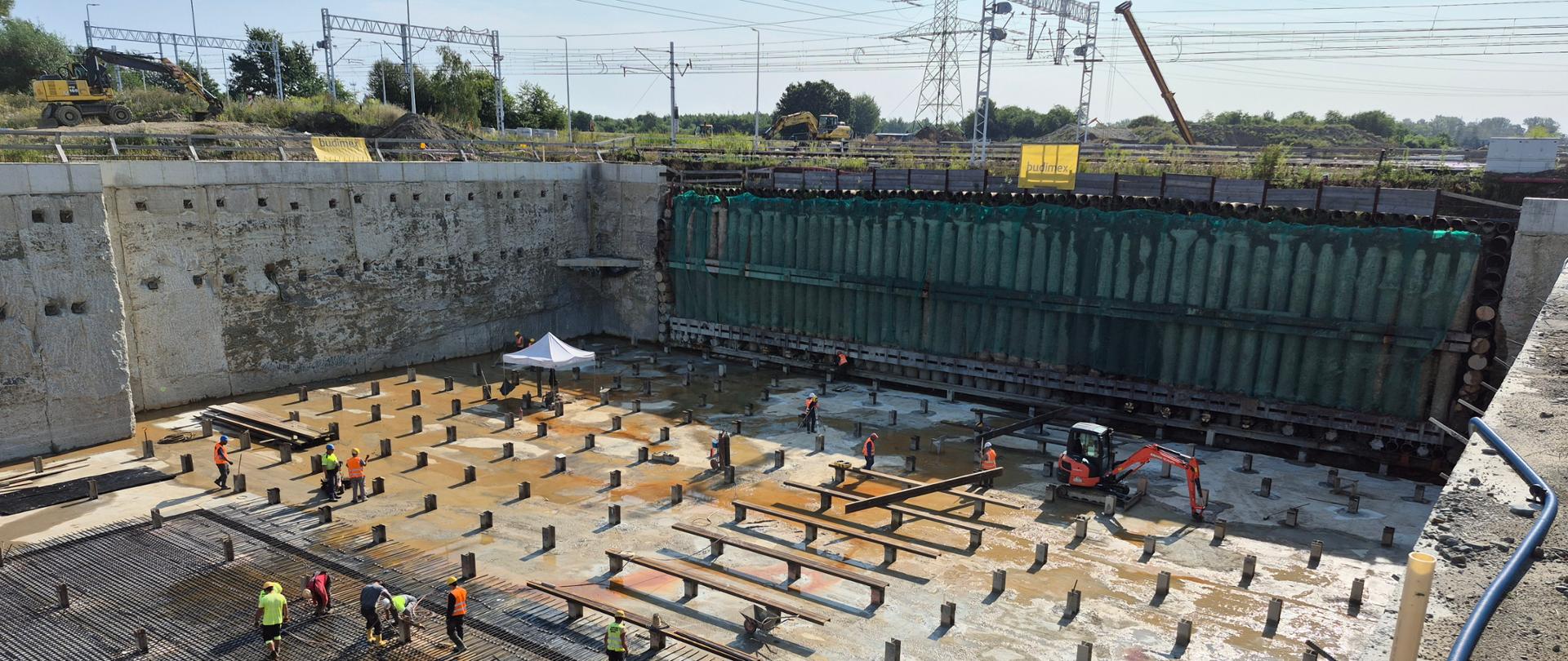 Budowa przejazdu pod torami kolejowymi, miejsce przygotowane do przecisku, zbrojenie podjazdu pod tory, w tle linia energetyczna