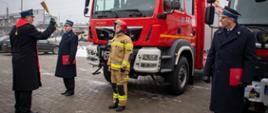 Poświęcenie przez kapelana straży pożarnej nowego ciężkiego samochodu ratowniczo-gaśniczego dla PSP w Grodzisku Mazowieckim. Przed samochodem stoi święcący go kapelan straży pożarnej, komendant powiatowy PSP w Grodzisku Mazowieckim, st. bryg Krzysztof Tryniszewski oraz kierowca z JRG w Grodzisku Mazowieckim.