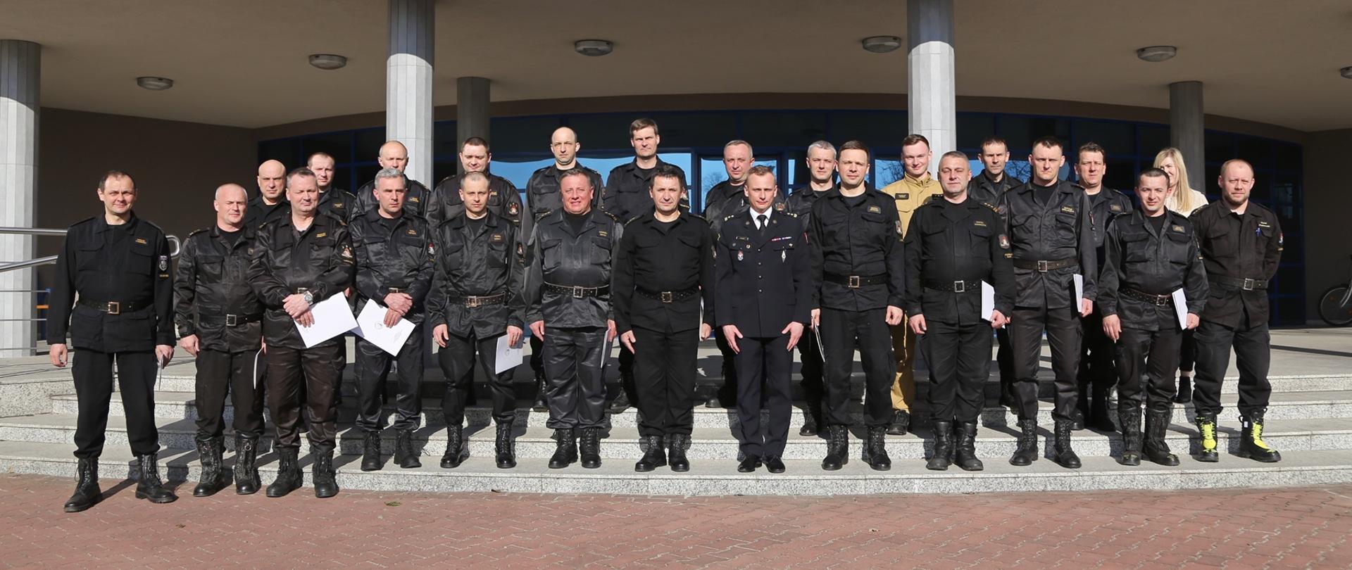 Grupowe zdjęcie uczestników szkolenia w towarzystwie Zastępcy Komendanta Centralnej Szkoły PSP oraz pracowników Szkoły sprawującymi nadzór nad szkoleniem