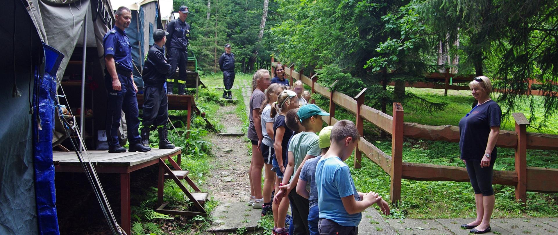 Dzieci na zbiórce stoją przed namiotami