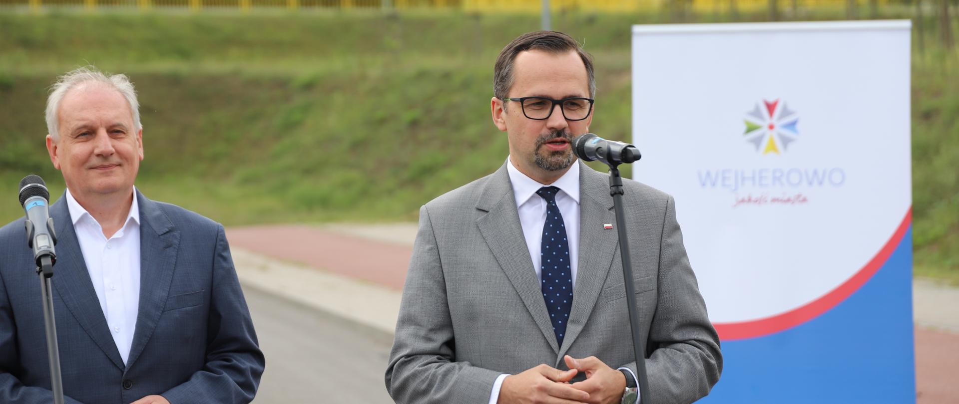 Wiceminister Marcin Horała stoi przed mikrofonem