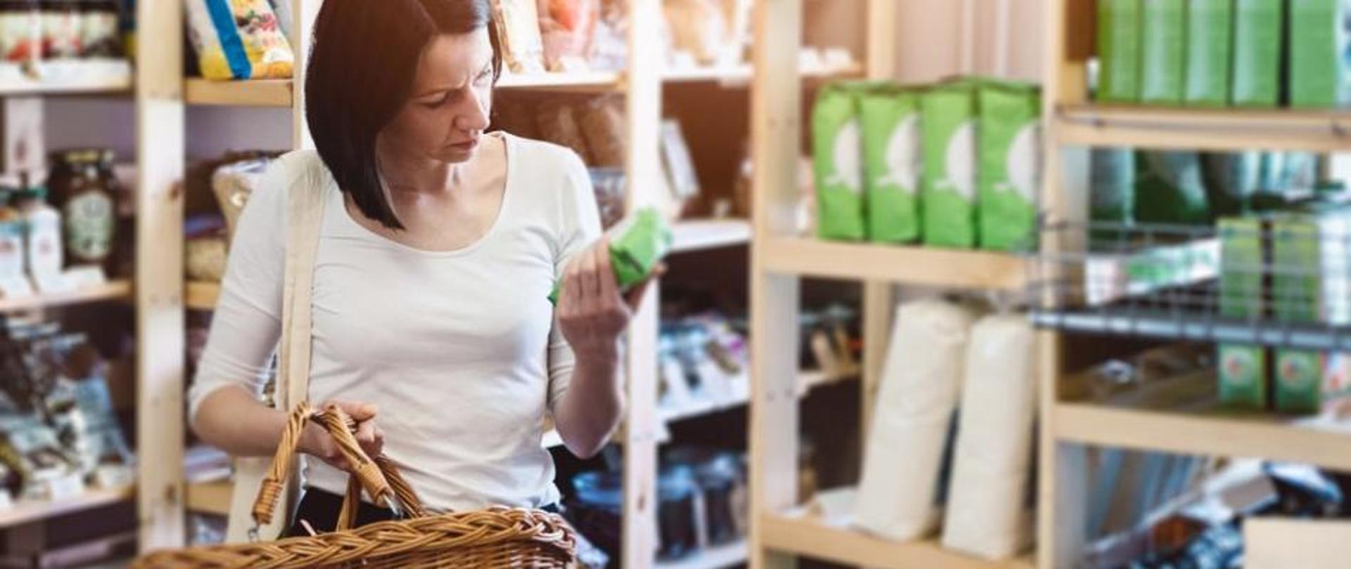 Kobieta w sklepie przygląda się etykietom na produktach