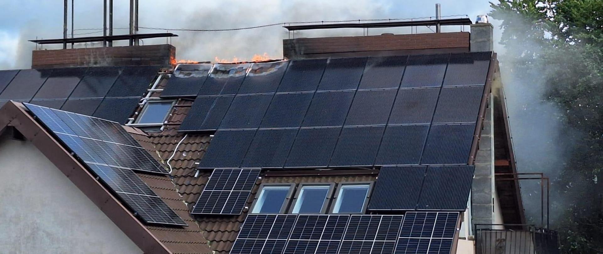 Palące się panele fotowoltaiczne zamocowane na brązowym dachu budynku wielorodzinnego.
