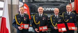 Zdjęcie przedstawia 4 funkcjonariuszy PSP, nagrodzonych podczas uroczystej zbiórki. 