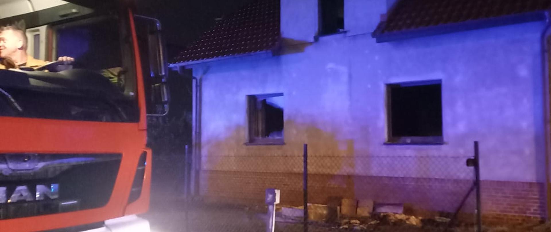 Samochód strażacki stoi obok domu mieszkalnego.