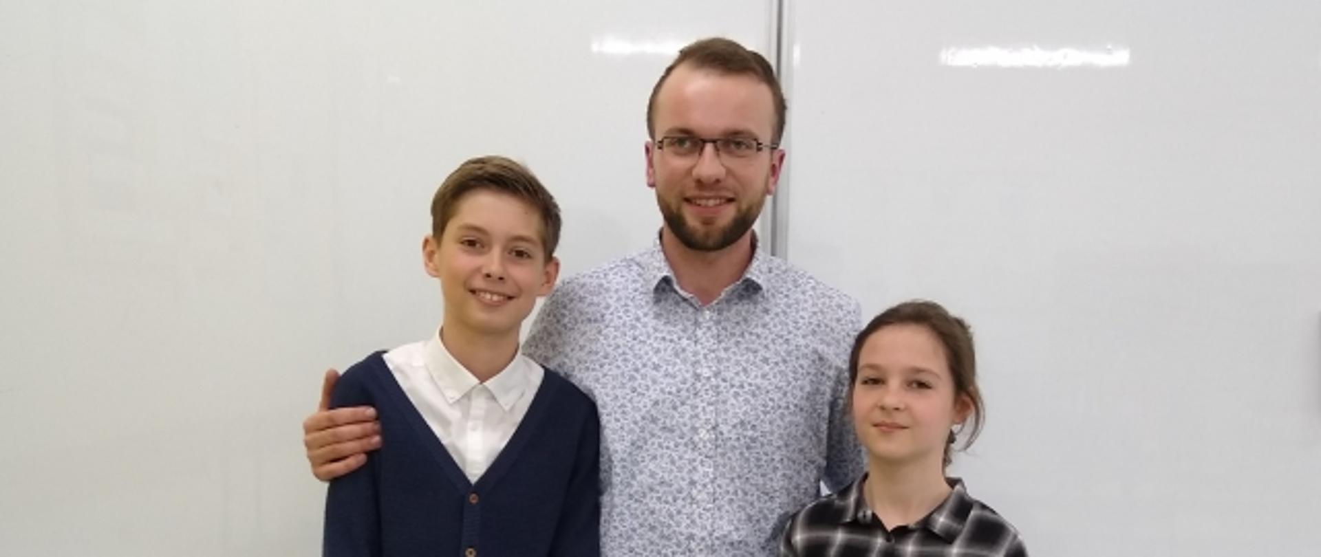 Dwoje uczniów wraz z nauczycielem na białym tle.