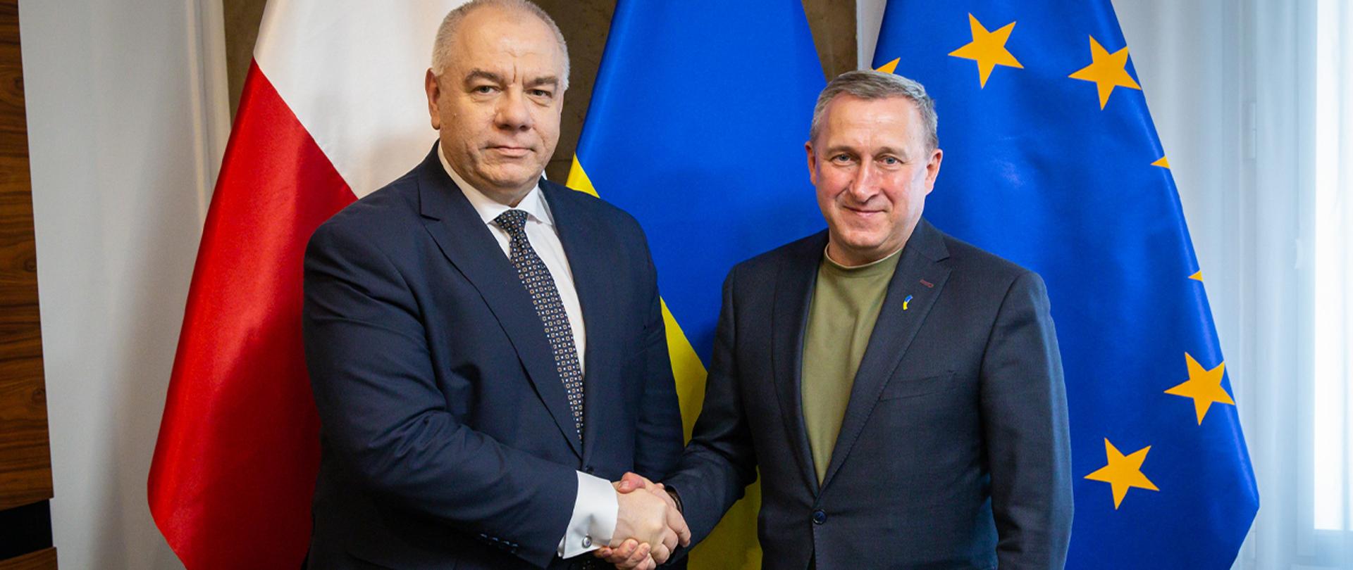 Wicepremier Jacek Sasin i Ambasador Ukrainy podczas spotkania. W tle flagi RP i Ukrainy.