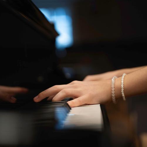 zdjęcie przedstawia zbliżenie na lewą dłoń uczennicy grającej na fortepianie