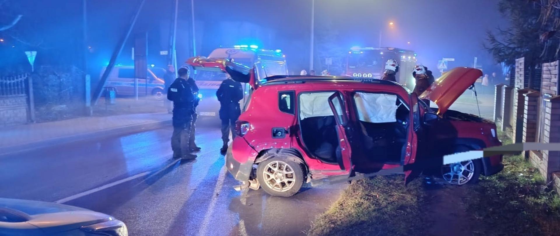 Uszkodzony czerwony samochód na poboczu, jest ciemno