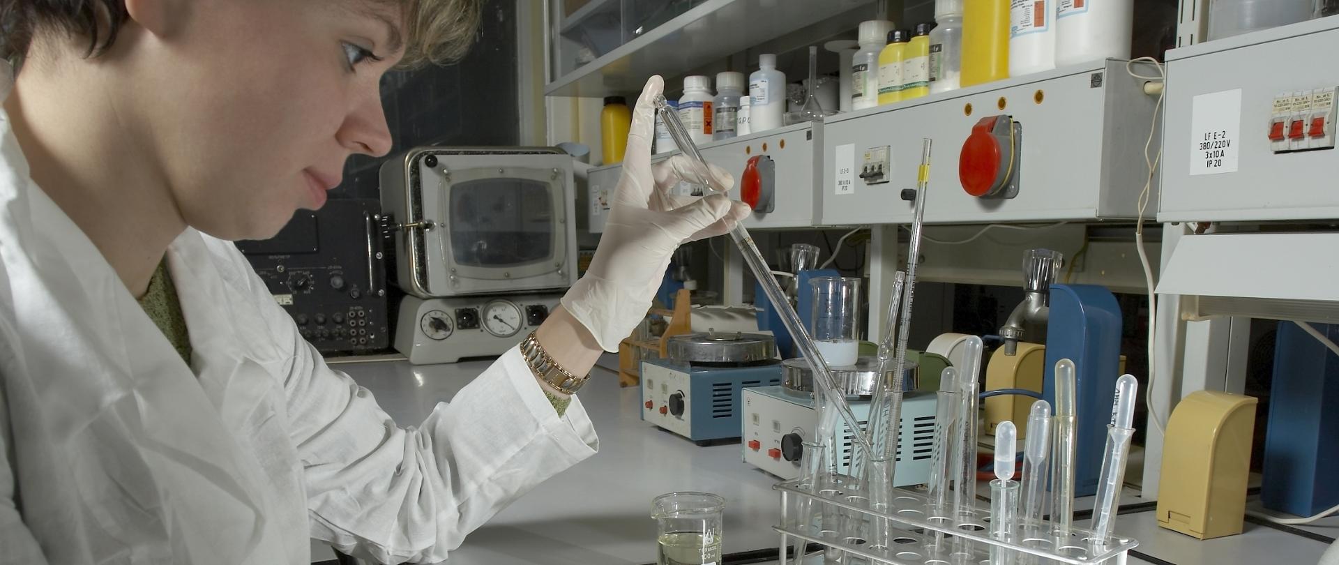 Kobieta w fartuchu pracuje w laboratorium chemicznym.