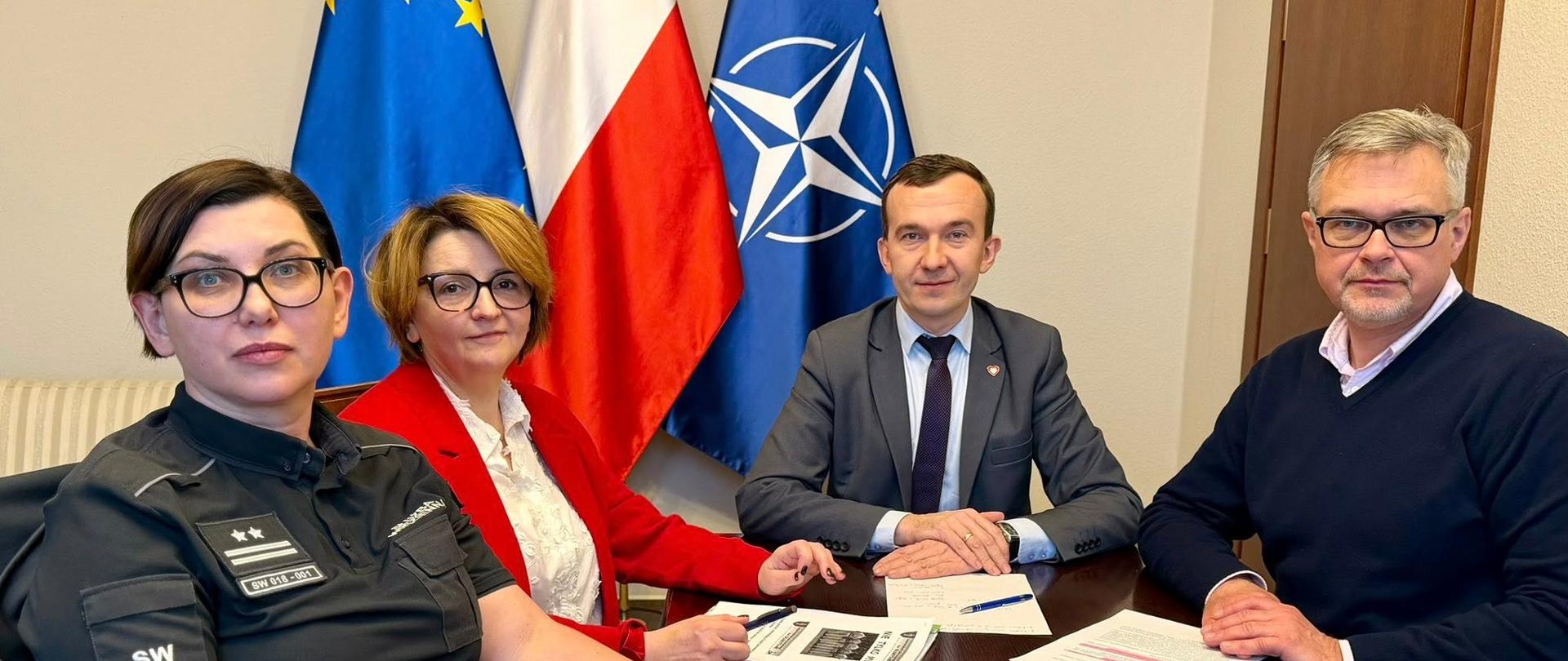 4 osoby, w tym Wicewojewoda, siedzą przy stole, pozują 