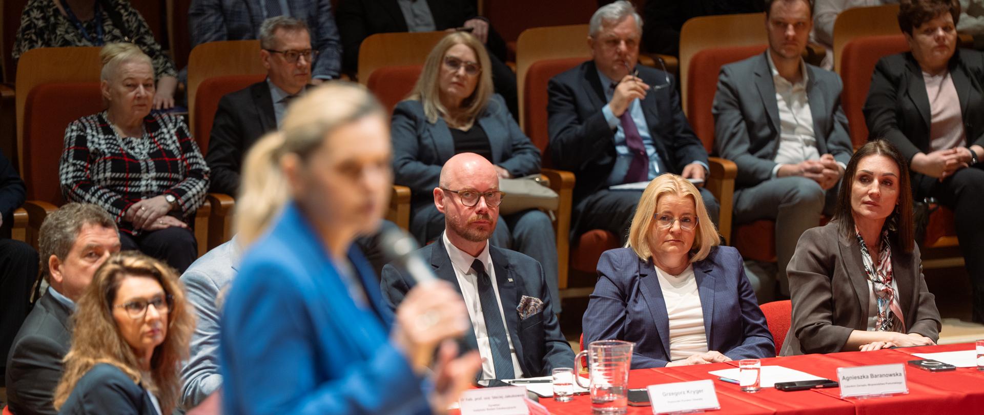 grupa osób siedzi za stołem prezydialnym 