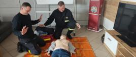 Strażacy na świetlicy podczas doskonalenia zawodowego z zakresu KPP z wykorzystaniem fantoma osoby dorosłej po podłączeniu AED