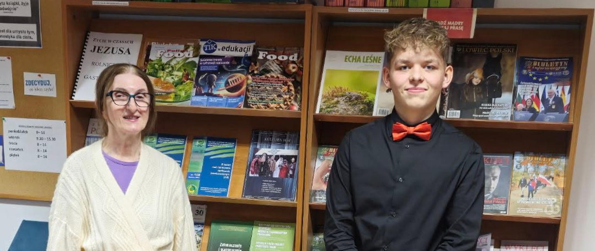 Kobieta i chłopak stoją na tle półek z czasopismami.
