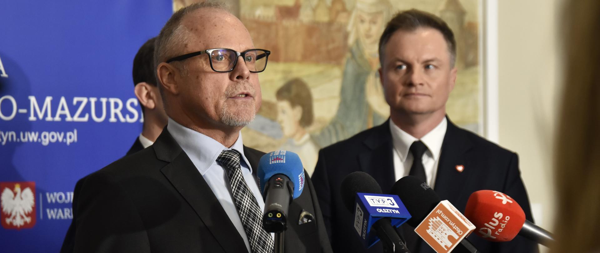 Wiceminister Jacek Prostas podczas briefingu mówi do mikrofonów