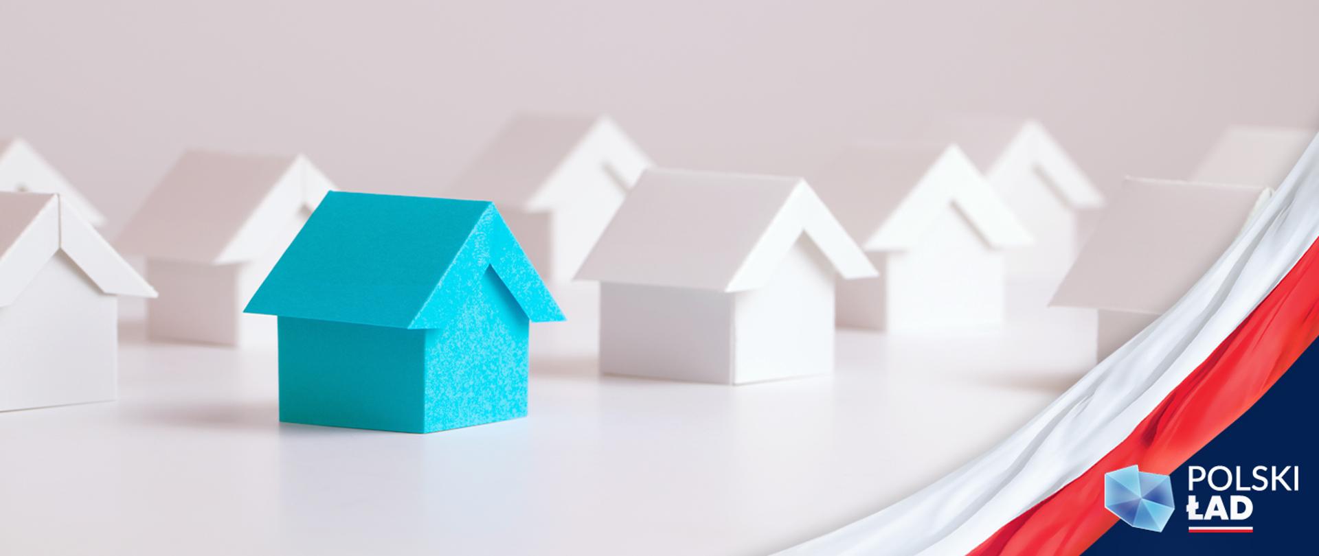 Na zdjęciu makieta z domkami jednorodzinnymi i biało czerwona flaga