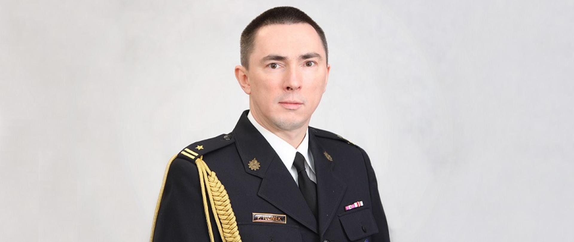 Piotr Tuzimek w mundurze galowym na janym tle