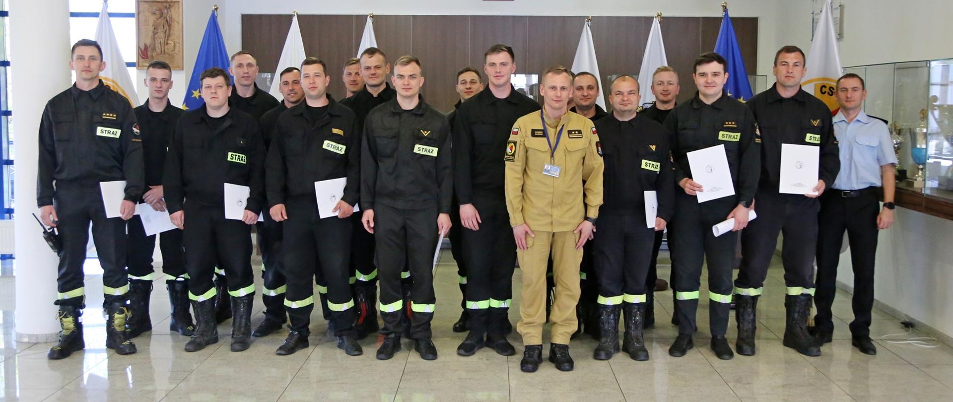 Grupowe zdjęcie uczestników szkolenia (16 osób) w towarzystwie Zastępcy Komendanta Centralnej Szkoły PSP oraz dwóch funkcjonariuszy Szkoły sprawującymi nadzór nad szkoleniem