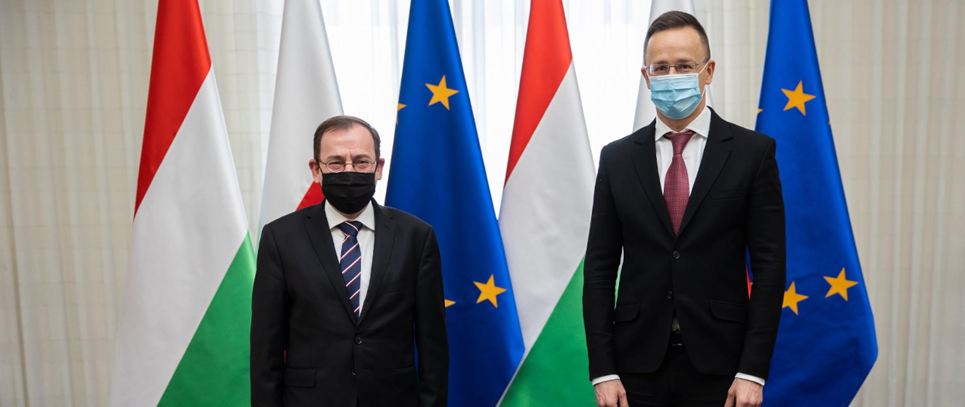 Na zdjęciu widać ministra Mariusza Kamińskiego i ministra spraw zagranicznych i handlu Węgier Pétera Szijjártó pozujących do zdjęcia na tle flag Polski, Węgier i UE.