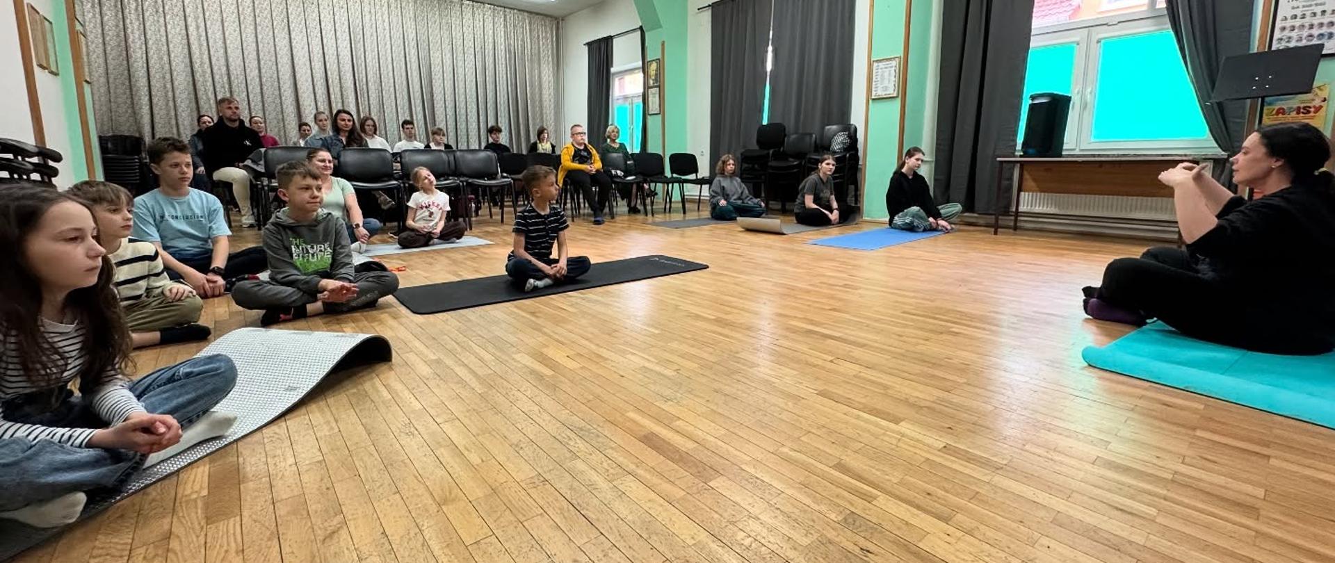 Zdjęcie przedstawiające uczestników warsztatów oddechowych prowadzonych przez panią Magdalenę Falewicz-Wesołowską, które odbyły się w auli szkoły 14 kwietnia 2025 roku.