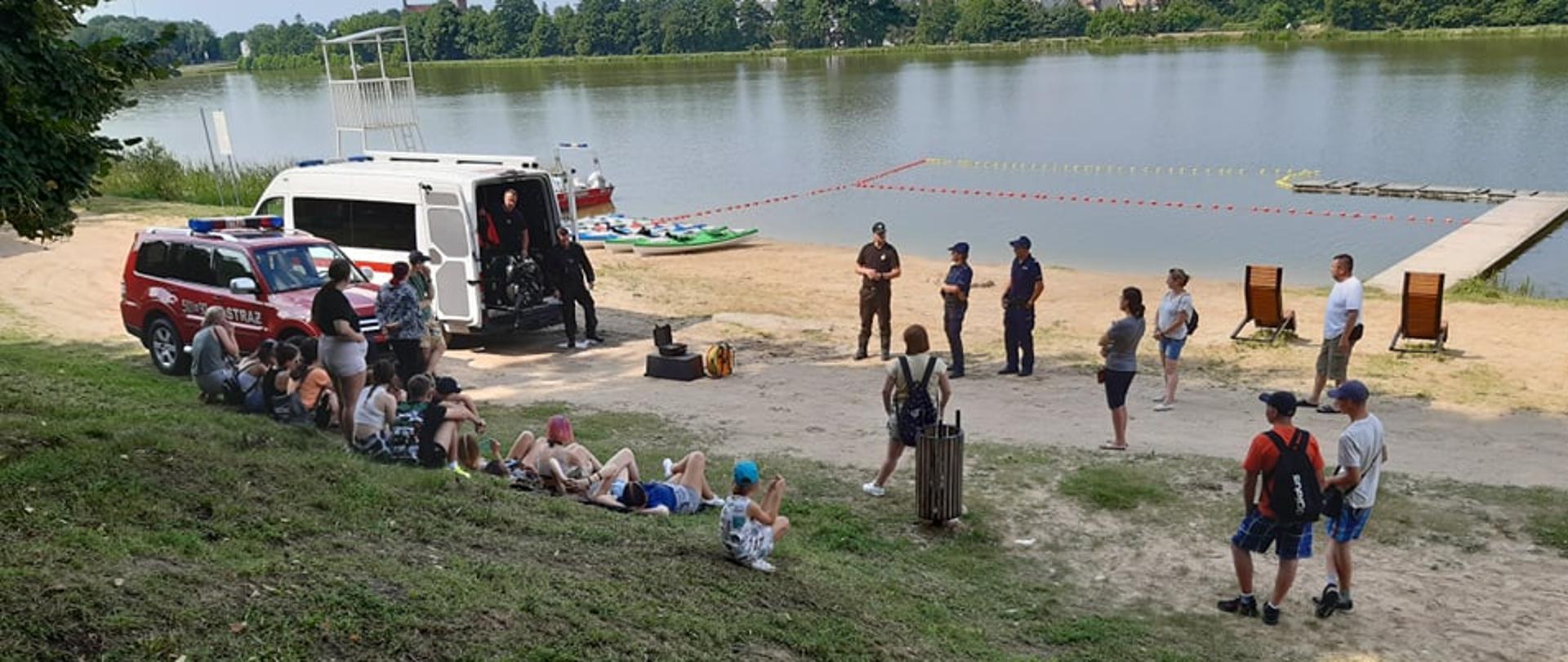 Strażacy przeprowadzają pogadankę na temat bezpieczeństwa nad wodą dla młodzieży na terenie zalewu miejskiego